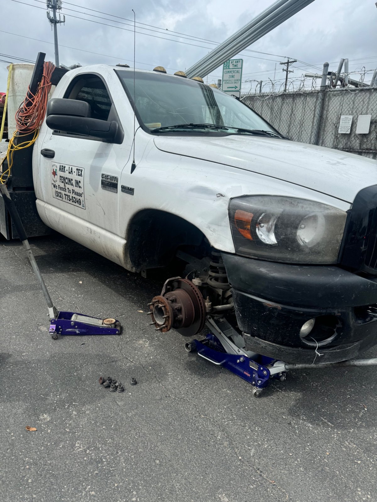 Dodge Ram work truck with both front wheels removed on jack stands during a heavy-duty mobile tire repair in Austin