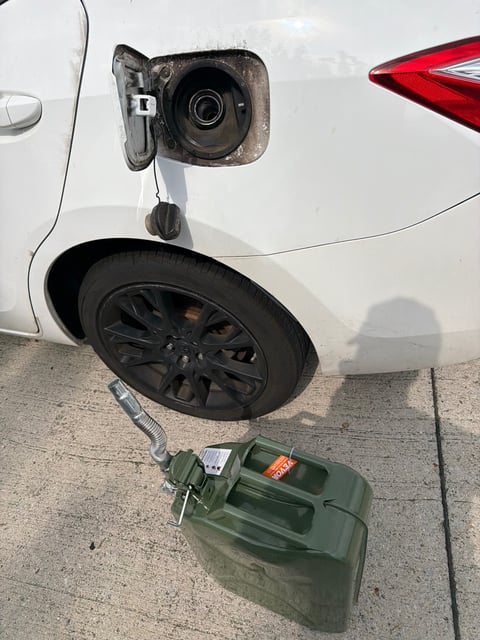 White Toyota Corolla stranded with an empty tank in the DFW metro, 5-gallon VEVOR jerry can staged at the open fuel door — All Hours Roadside 24/7 mobile fuel delivery