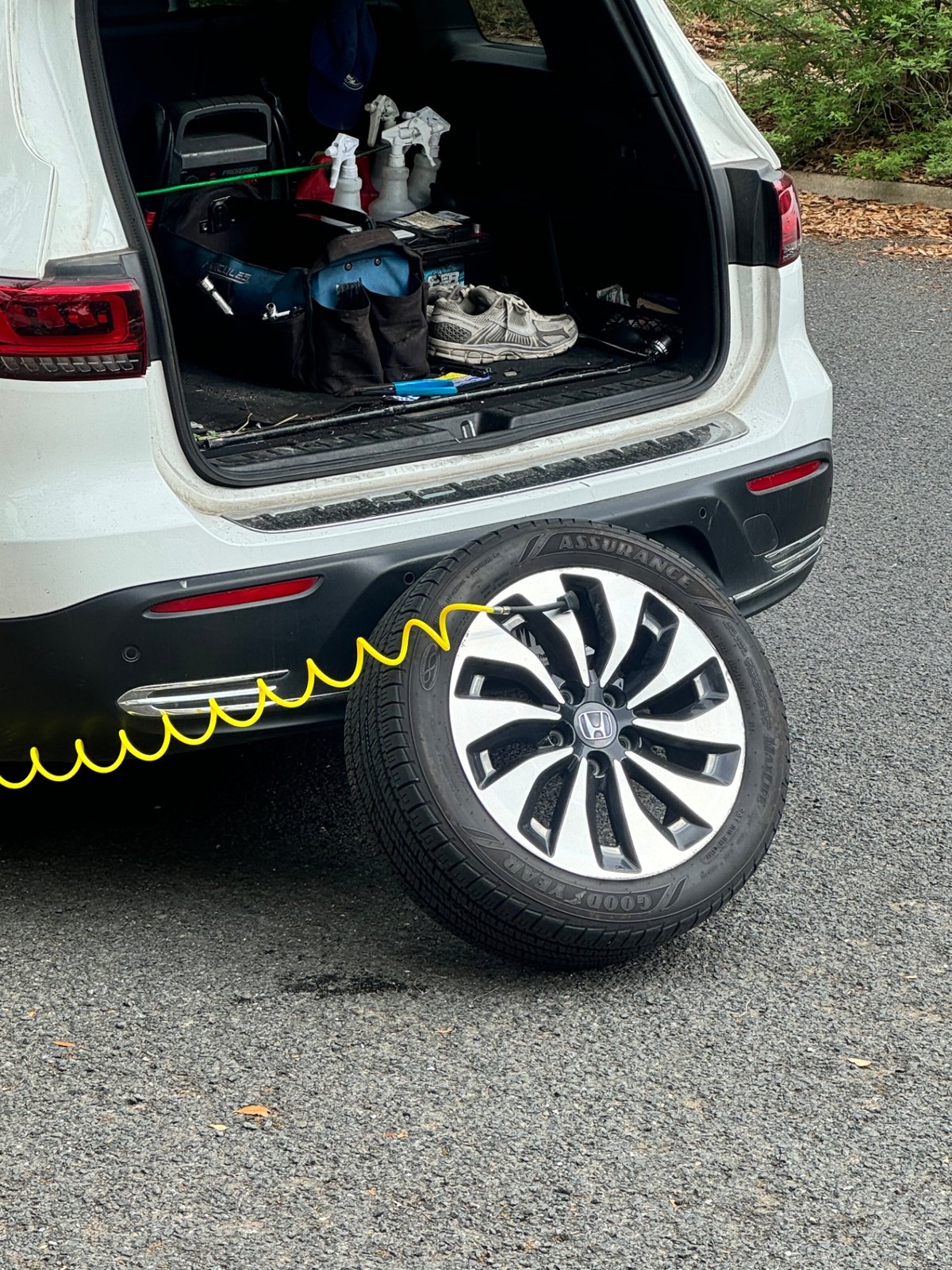 Honda spare tire mounted with a yellow coil air hose being attached by an All Hours Roadside technician in an Austin neighborhood