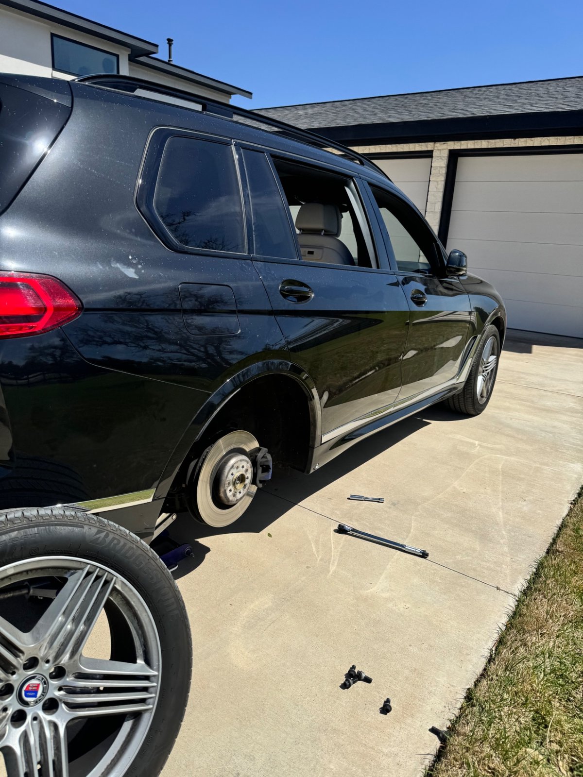 BMW X7 wheel removed and tire being swapped by All Hours Roadside technician in a Dallas driveway