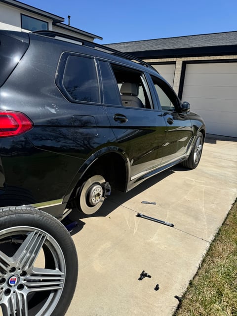 BMW X7 wheel removed and tire being swapped by All Hours Roadside technician in a Dallas driveway