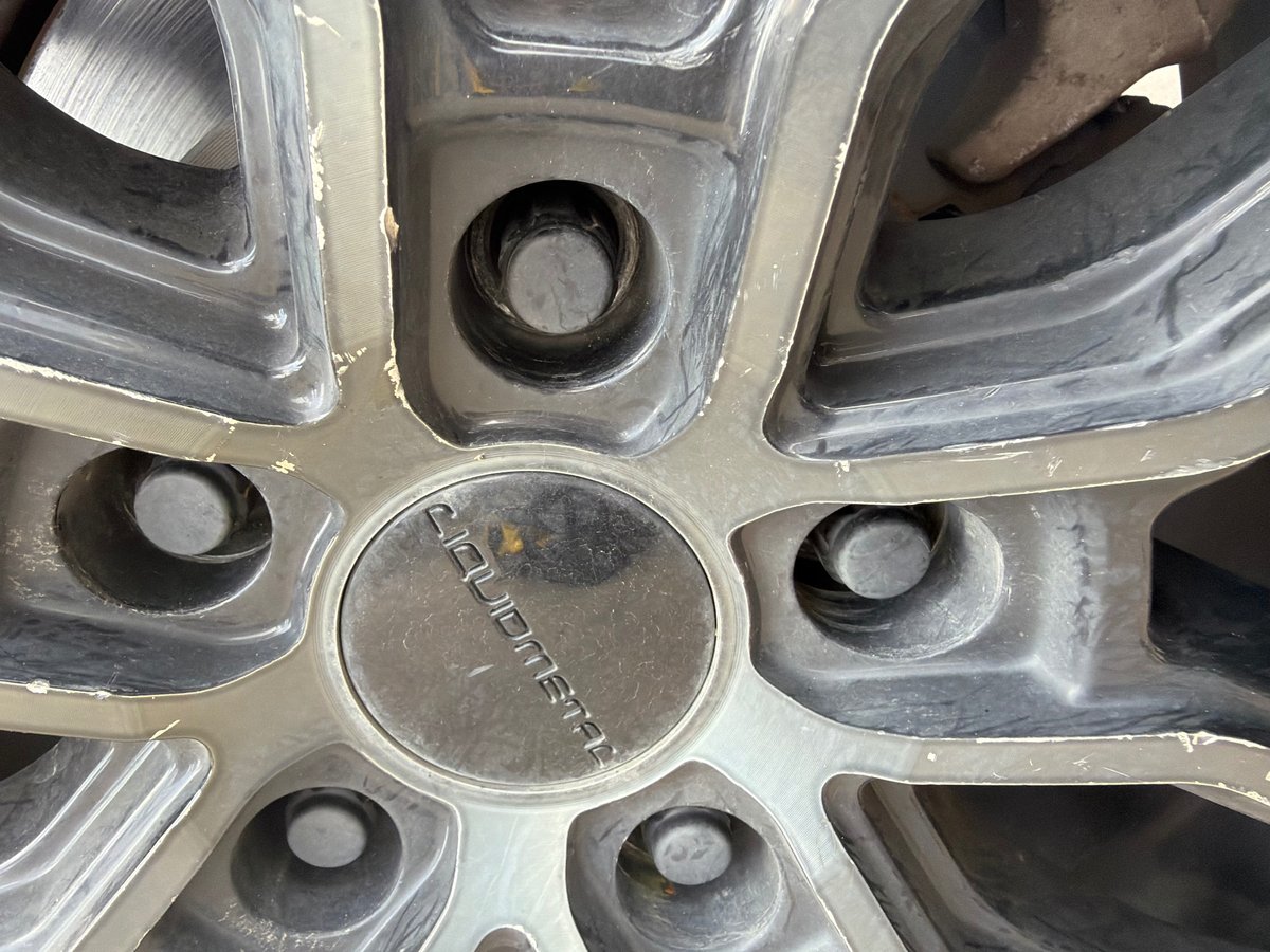 Recessed factory Mazda wheel lock inside a gray Liquidmetal alloy wheel with center cap — removed on-site without a key and with zero damage to the rim by All Hours Roadside in the Dallas–Fort Worth metro
