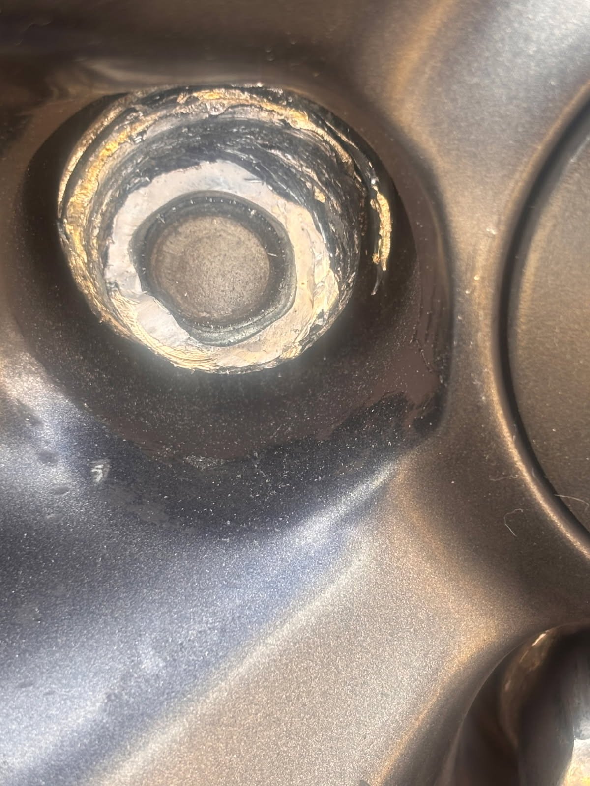 Close-up of a stripped lug nut with a completely rounded hex head recessed inside a steel wheel lug pocket — extracted on-site by All Hours Roadside in the Dallas–Fort Worth metro