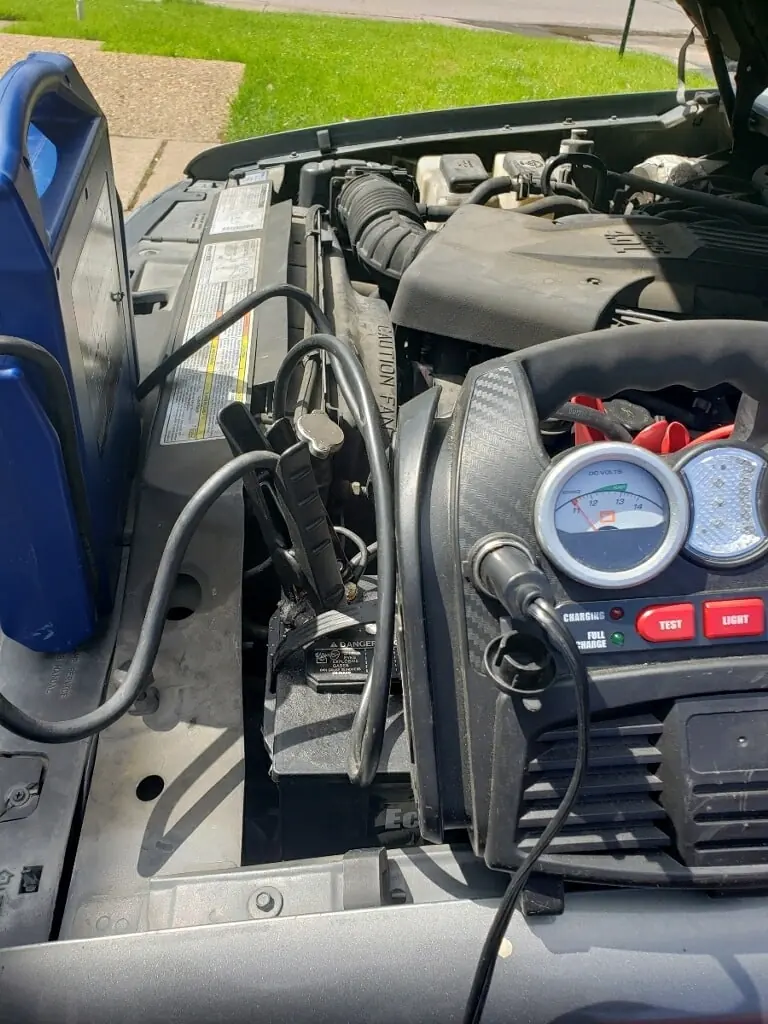 Professional jump pack clamped to a vehicle battery in Dallas with the voltmeter showing a healthy 14 volts after the jump start