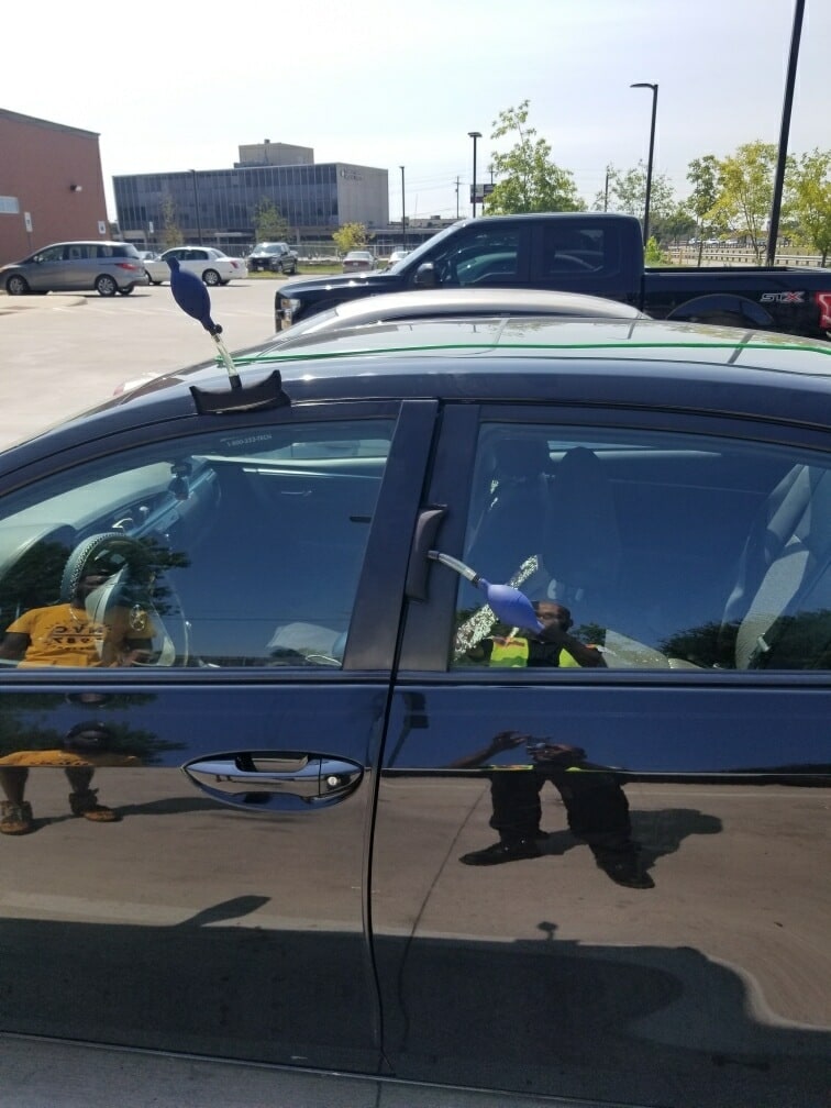 All Hours Roadside technician using a professional air wedge and long-reach tool to unlock a dark sedan in a Dallas parking lot