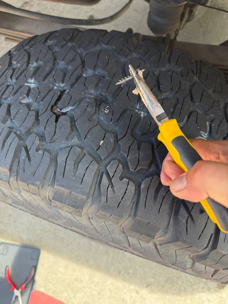 Close-up of a screw being removed from the tread during a mobile tire repair plug service