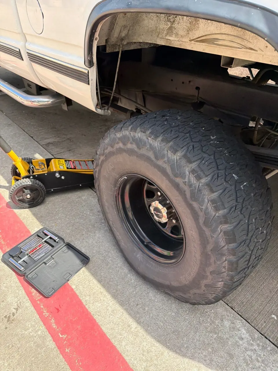 Mobile tire repair setup beside a truck at a home or office parking space before starting the on-site plug repair